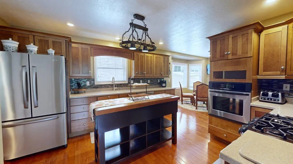 The kitchen from the far end, refrigerator and pendant lights over the island