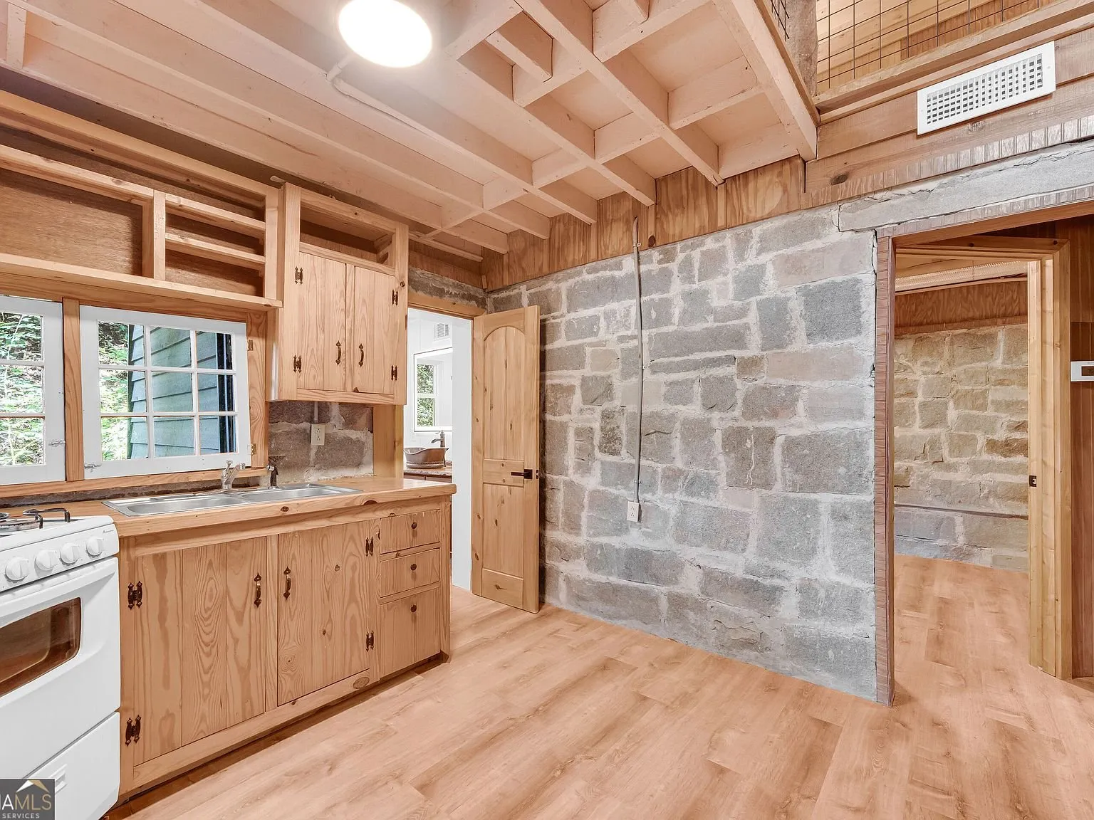 A bedroom with stone walls and a window looking into the trees