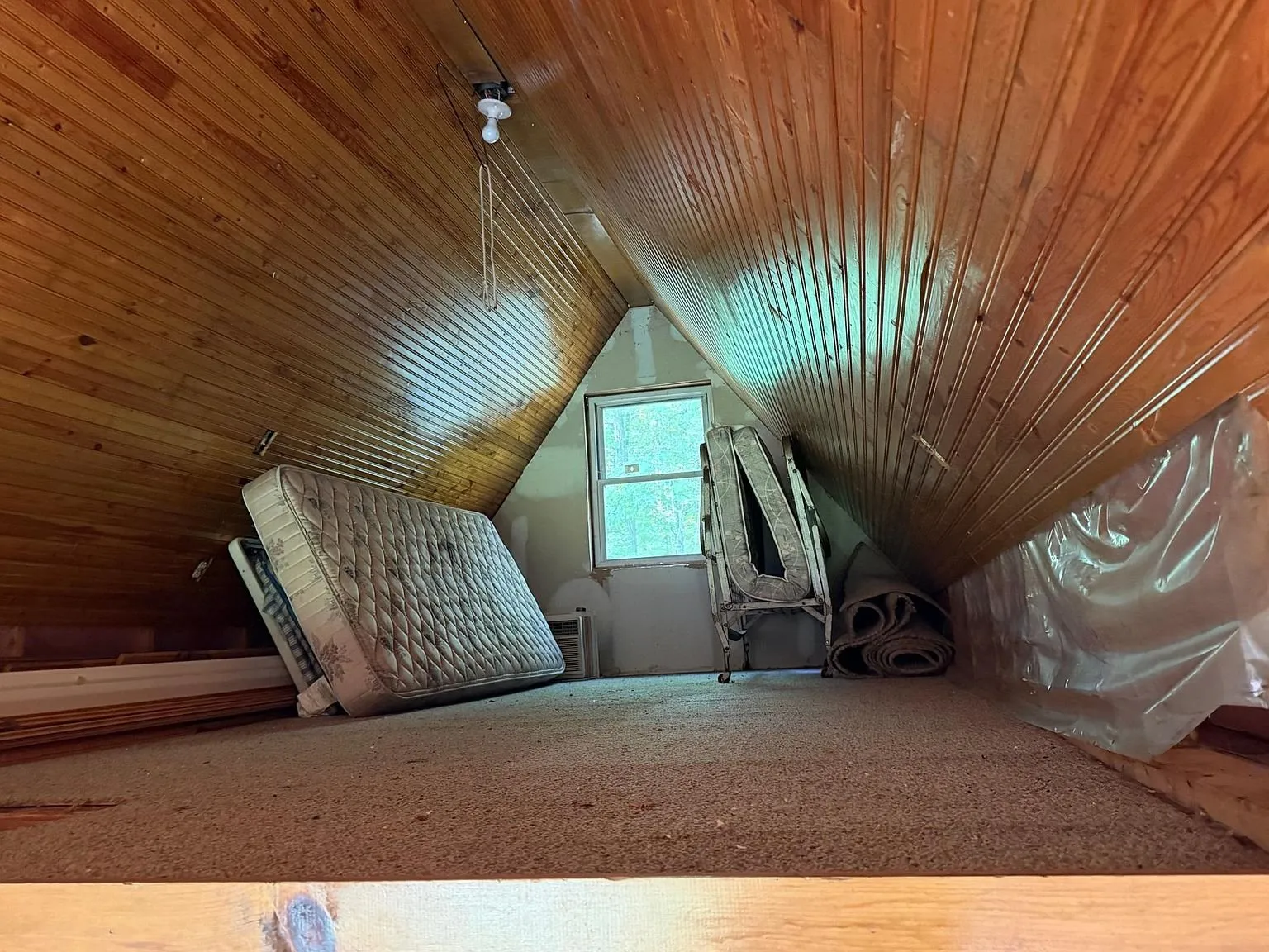 The loft under the peak with the window and the ceiling fan