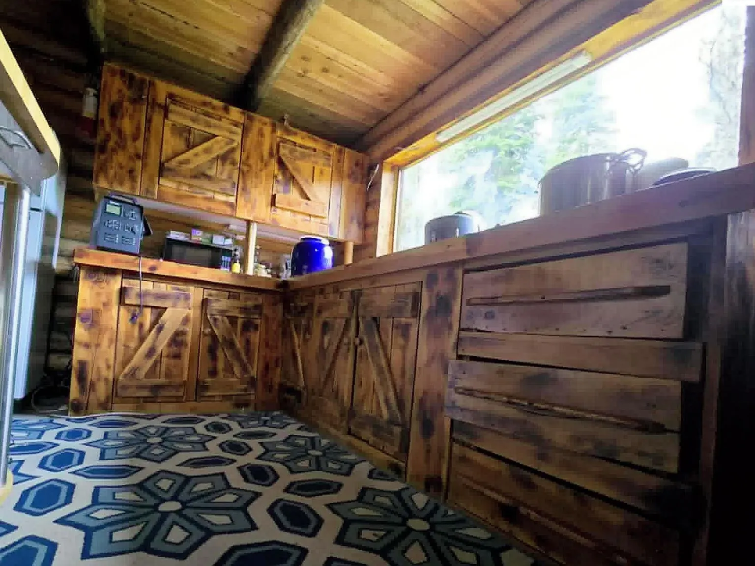 The kitchenette with barn-door style cabinetry and a patterned floor rug