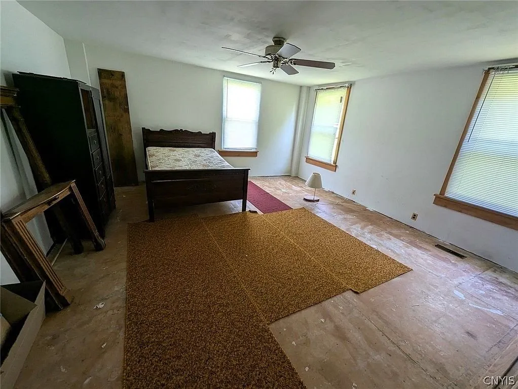 A bedroom with the bed frame and a mirror against the wall