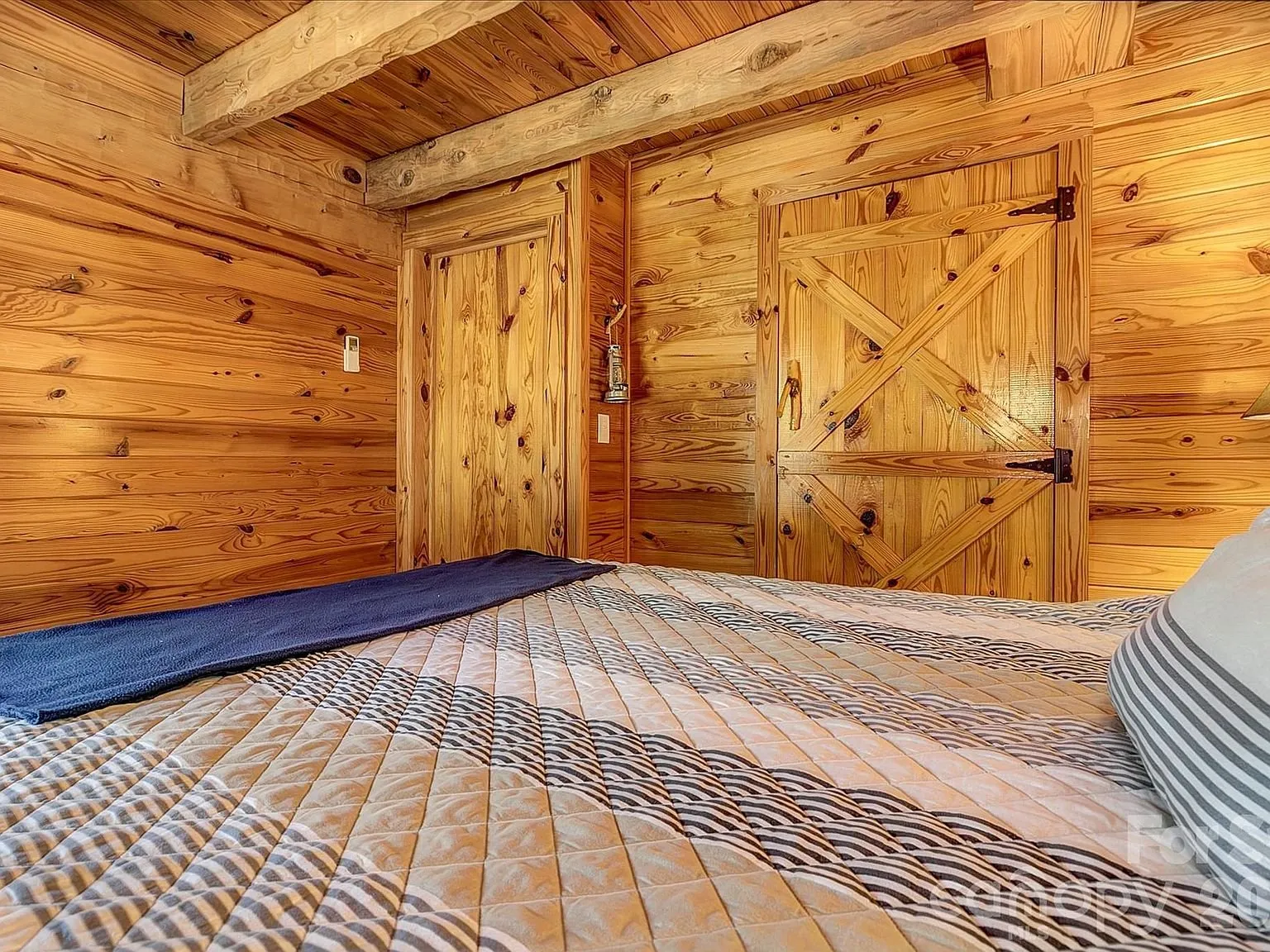 An unfurnished room with exposed log walls and a barn-style door