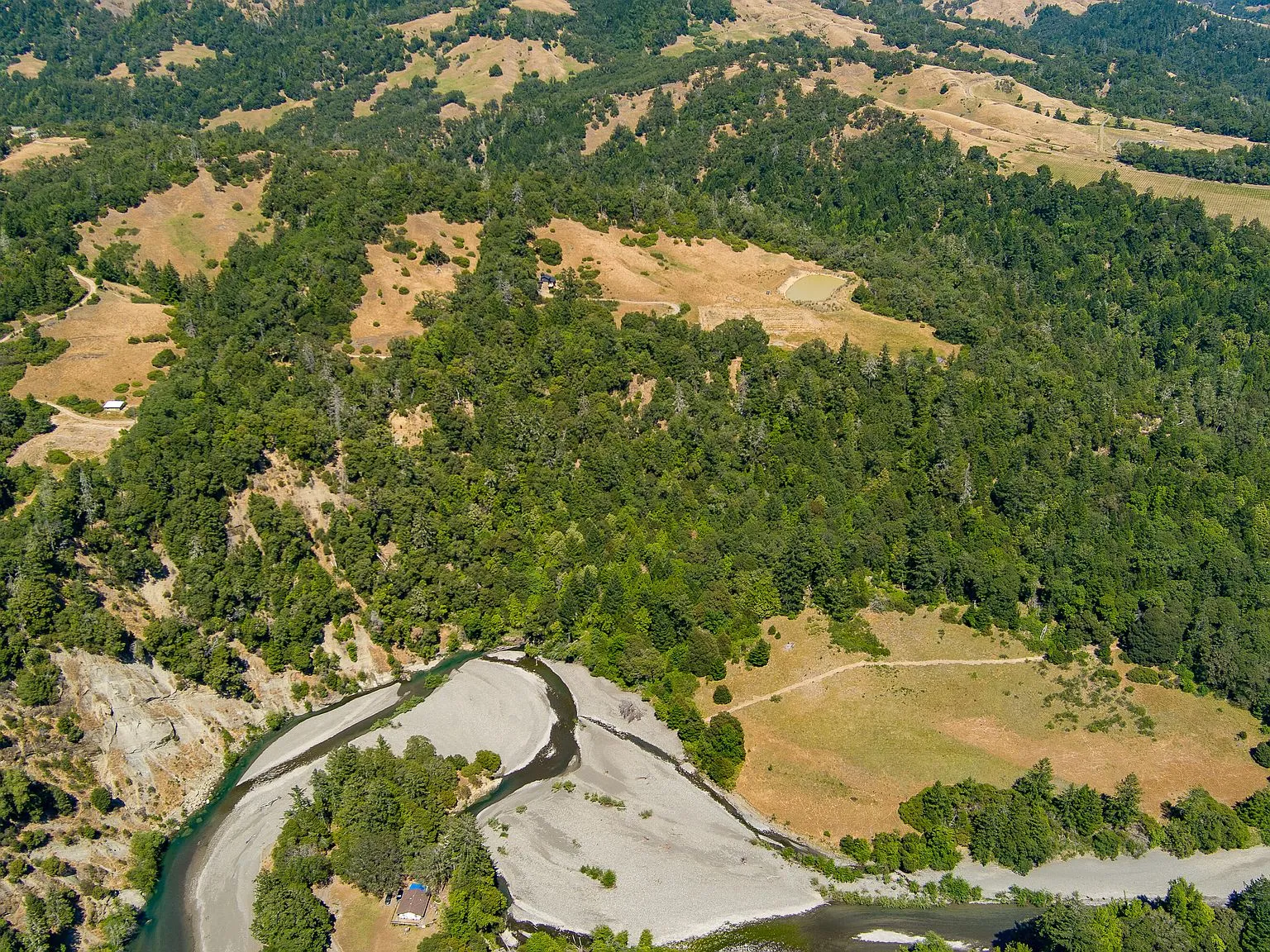An aerial view of the house and driveway winding through the meadow