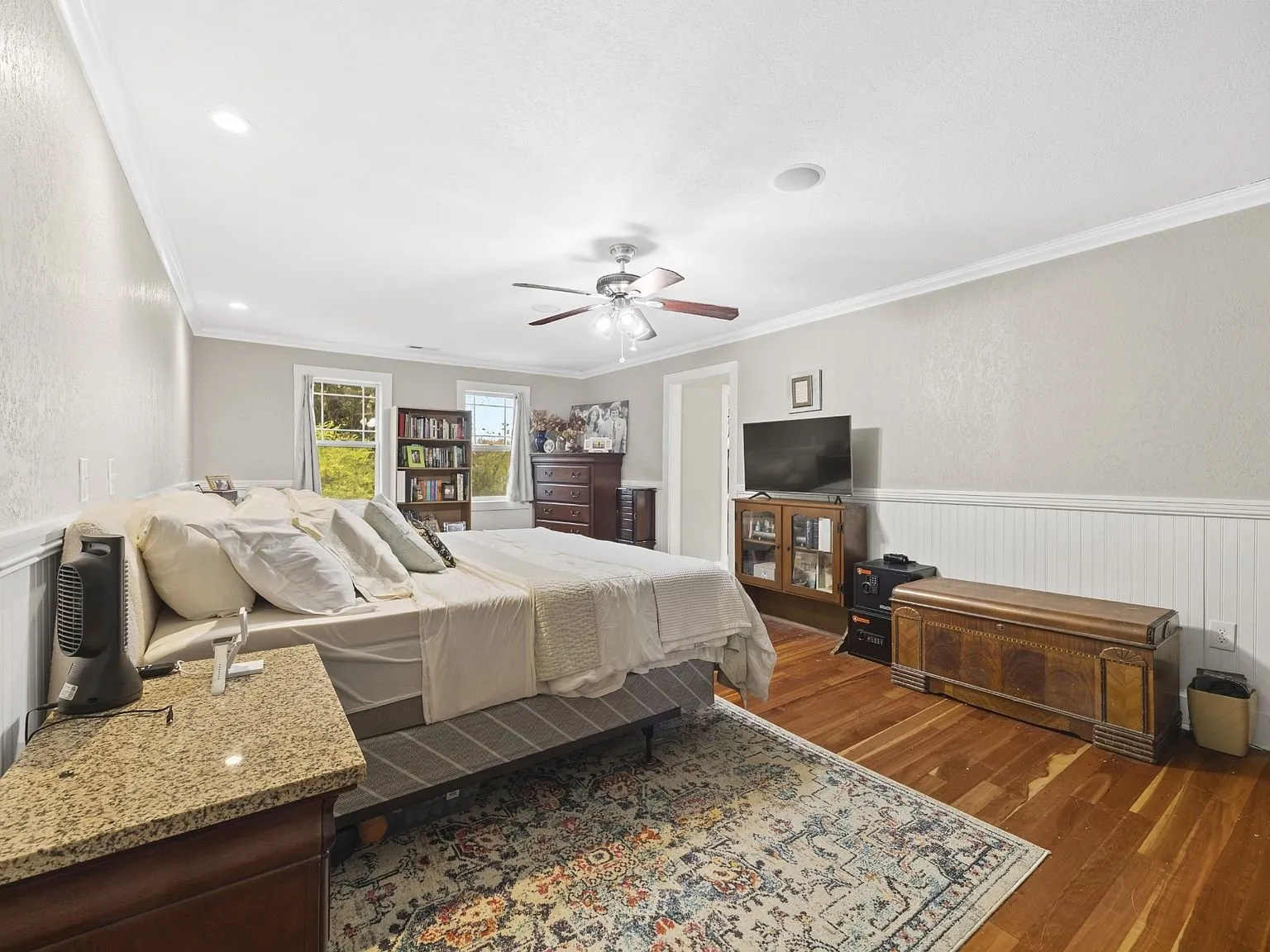 Bedroom with wood floors, a window, and a wainscoted wall