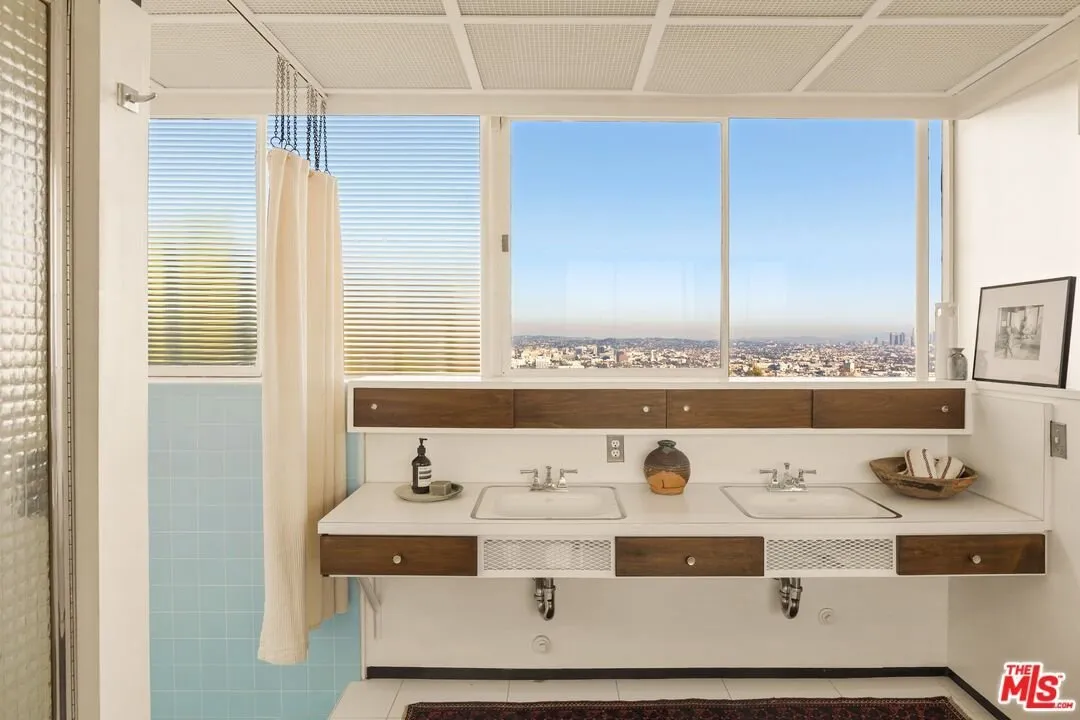 A bathroom with twin basins and a window onto the hillside