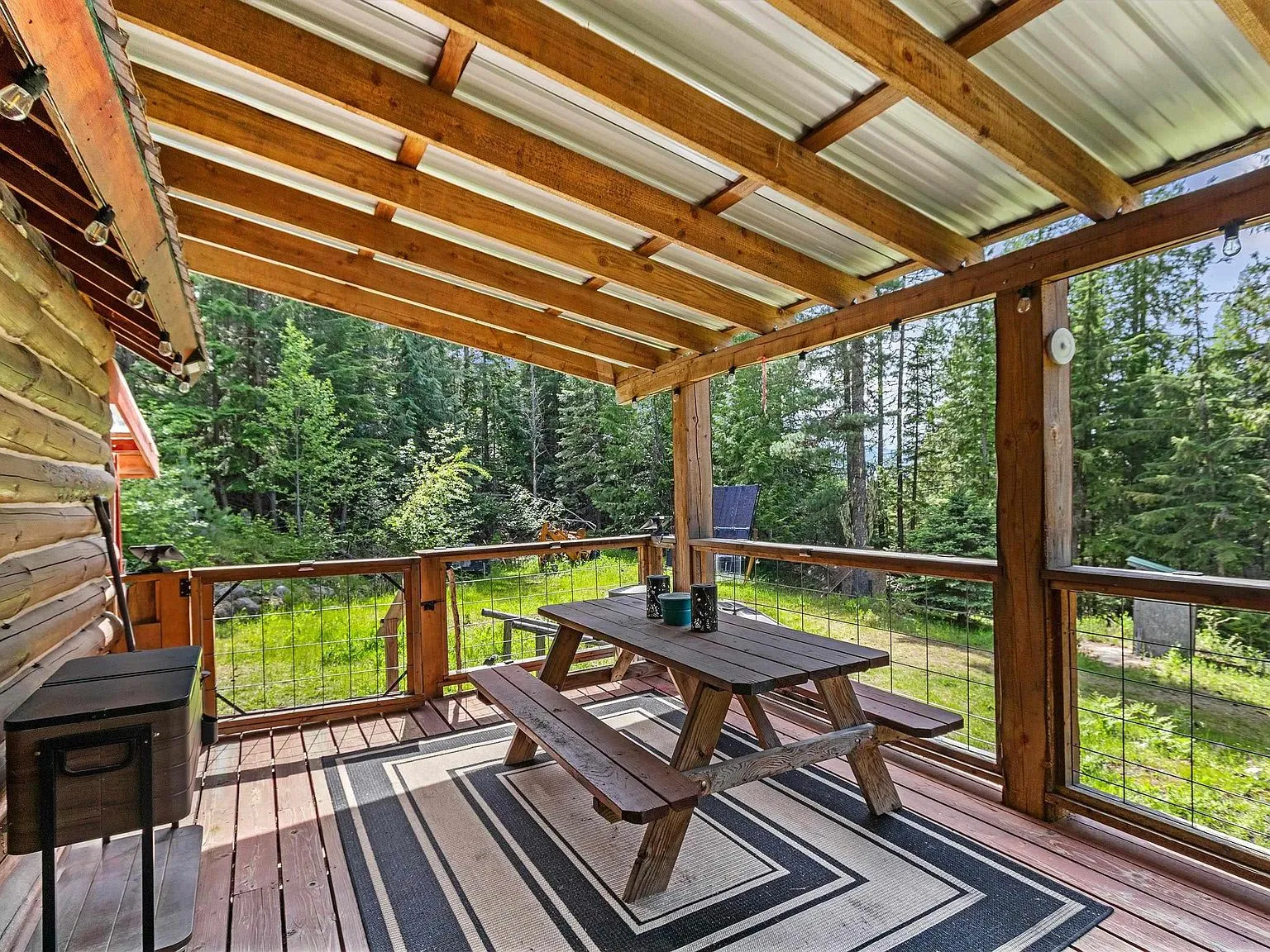 The covered deck's metal roof, picnic table and gas grill overlooking the yard