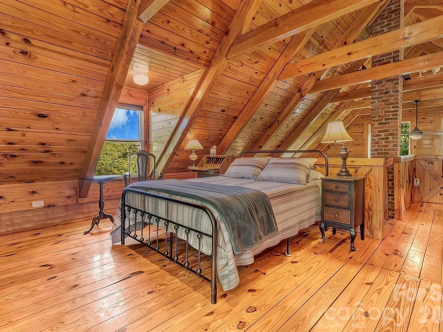 The upstairs loft bedroom with a metal bed frame beneath the sloped ceiling