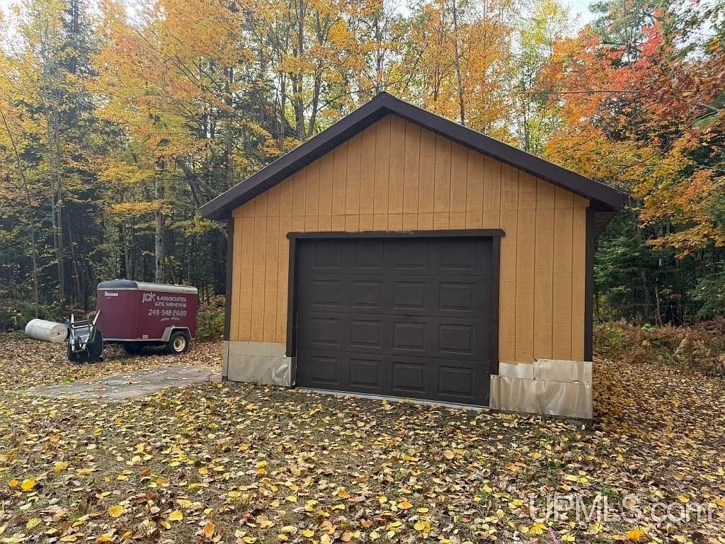 The detached garage with its overhead door among the trees