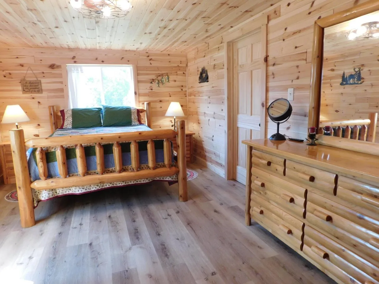 The bedroom with a log bed, dresser and knotty pine walls