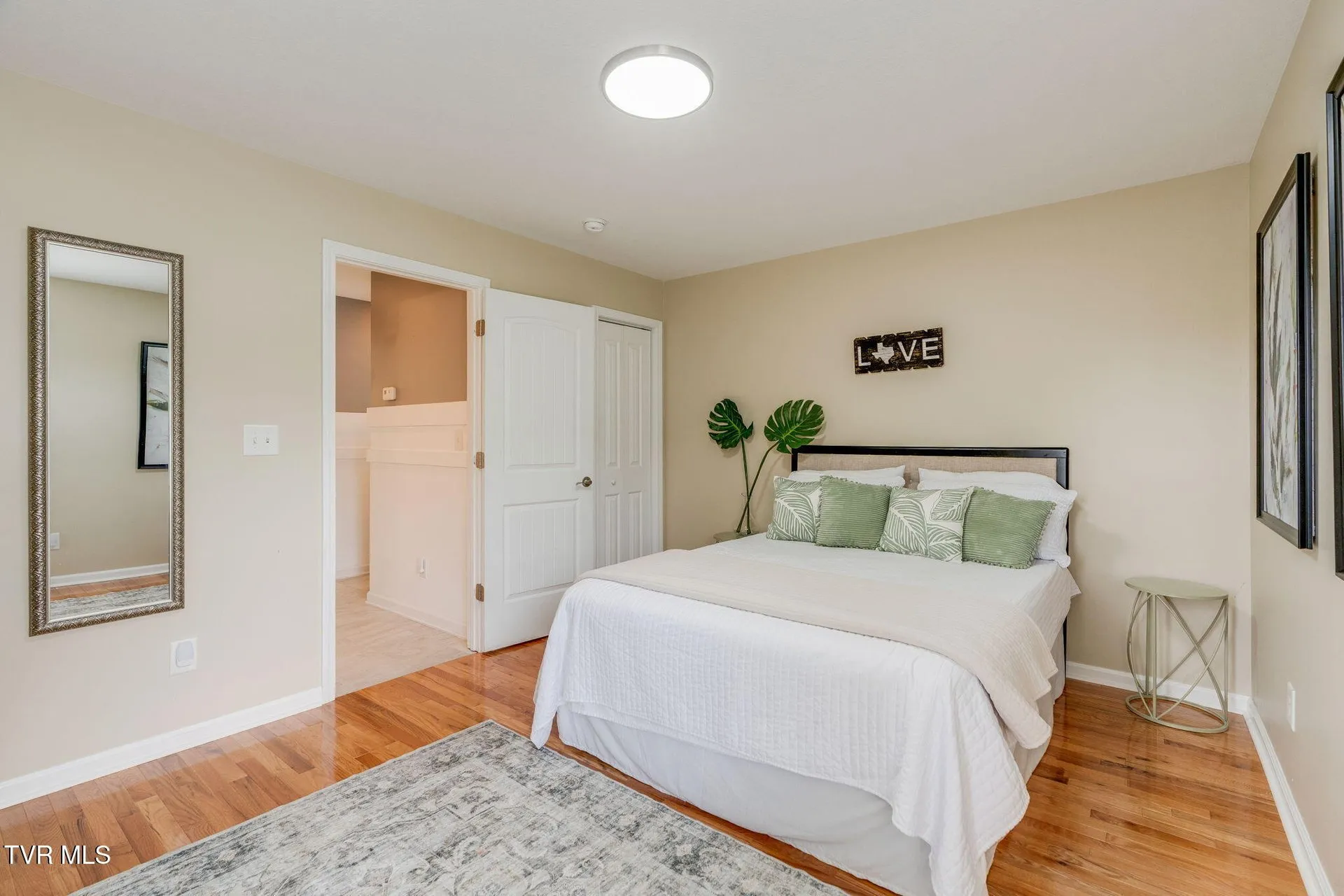 The main-floor bedroom from the doorway with hardwood in the hall beyond