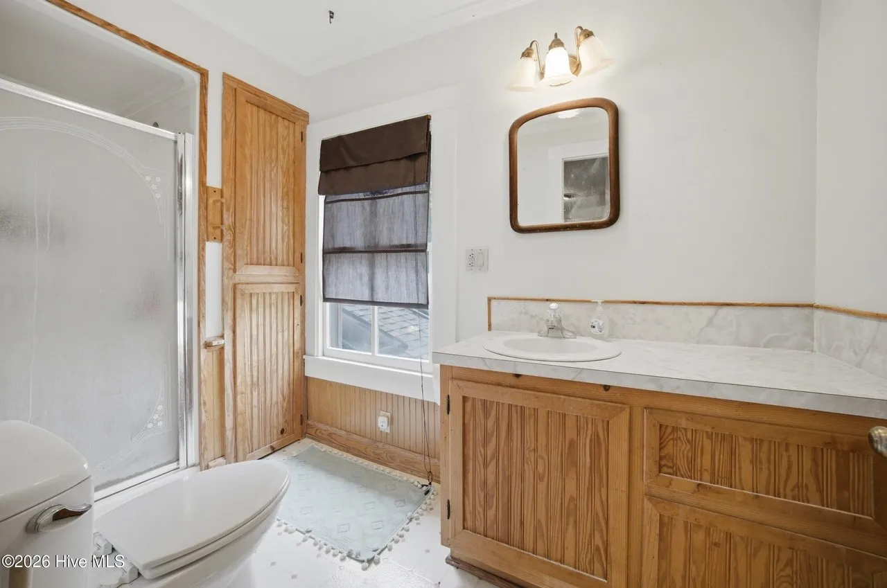 Bathroom with a shower stall, wood vanity, and beadboard