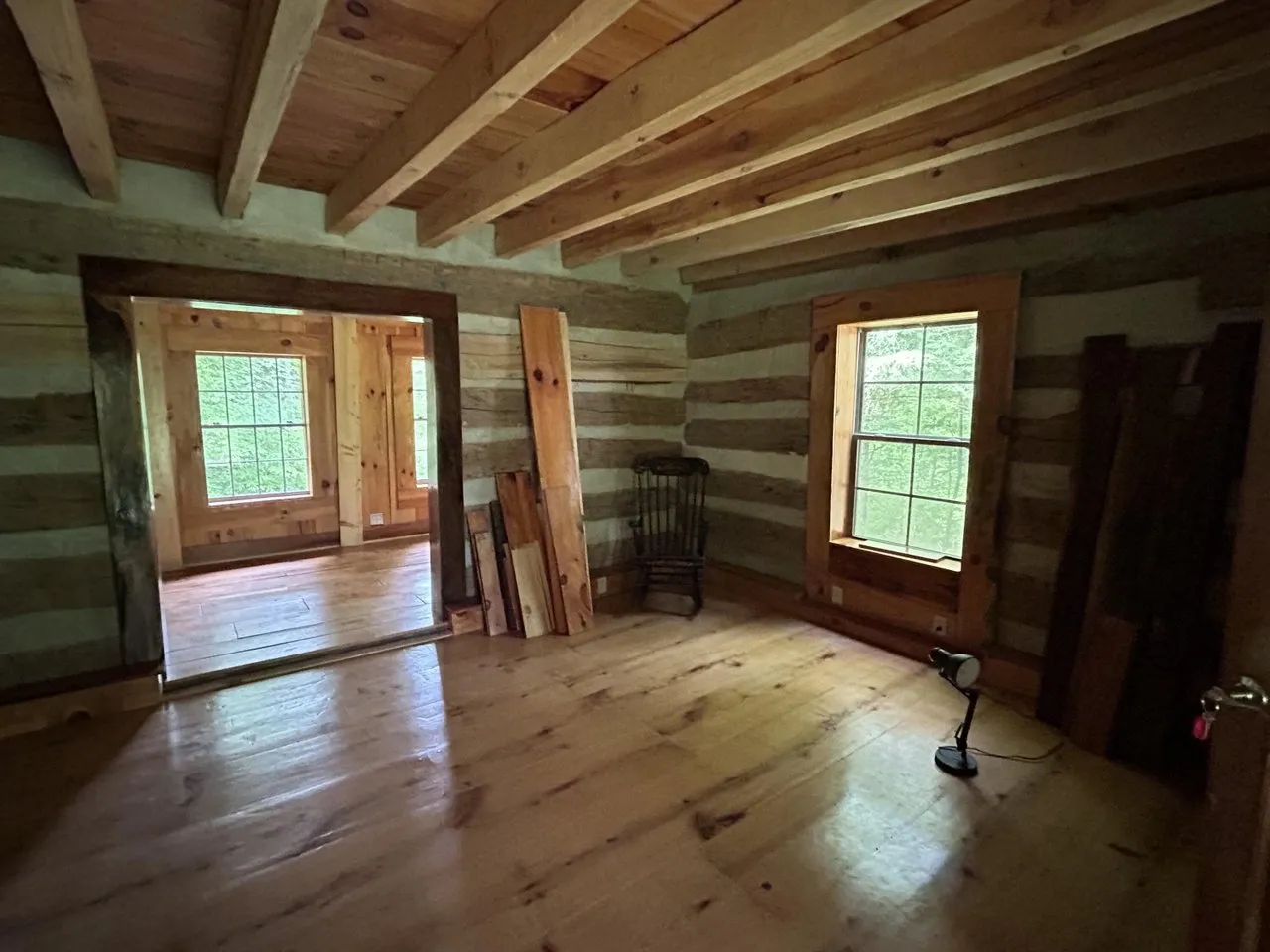 Inside the log cabin: hewn log walls, wide plank floors and windows on two sides
