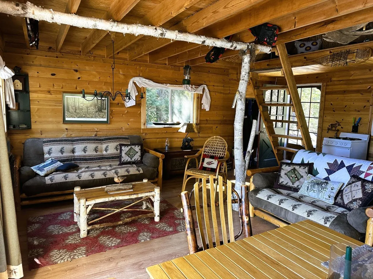 The main room with log walls, futon and the ladder to the loft