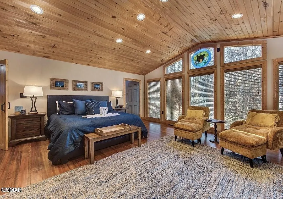 A bedroom with a bench at the foot of the bed and a wall of windows