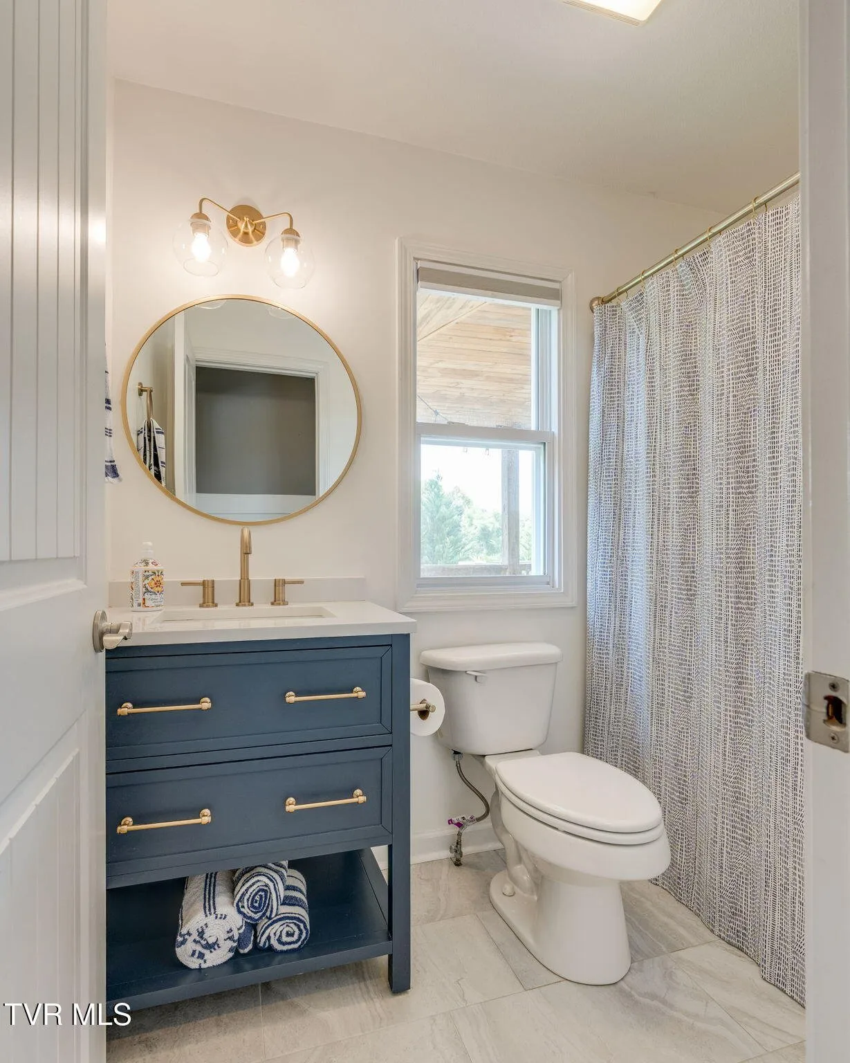 The main-floor full bathroom with a vanity, mirror and framed art