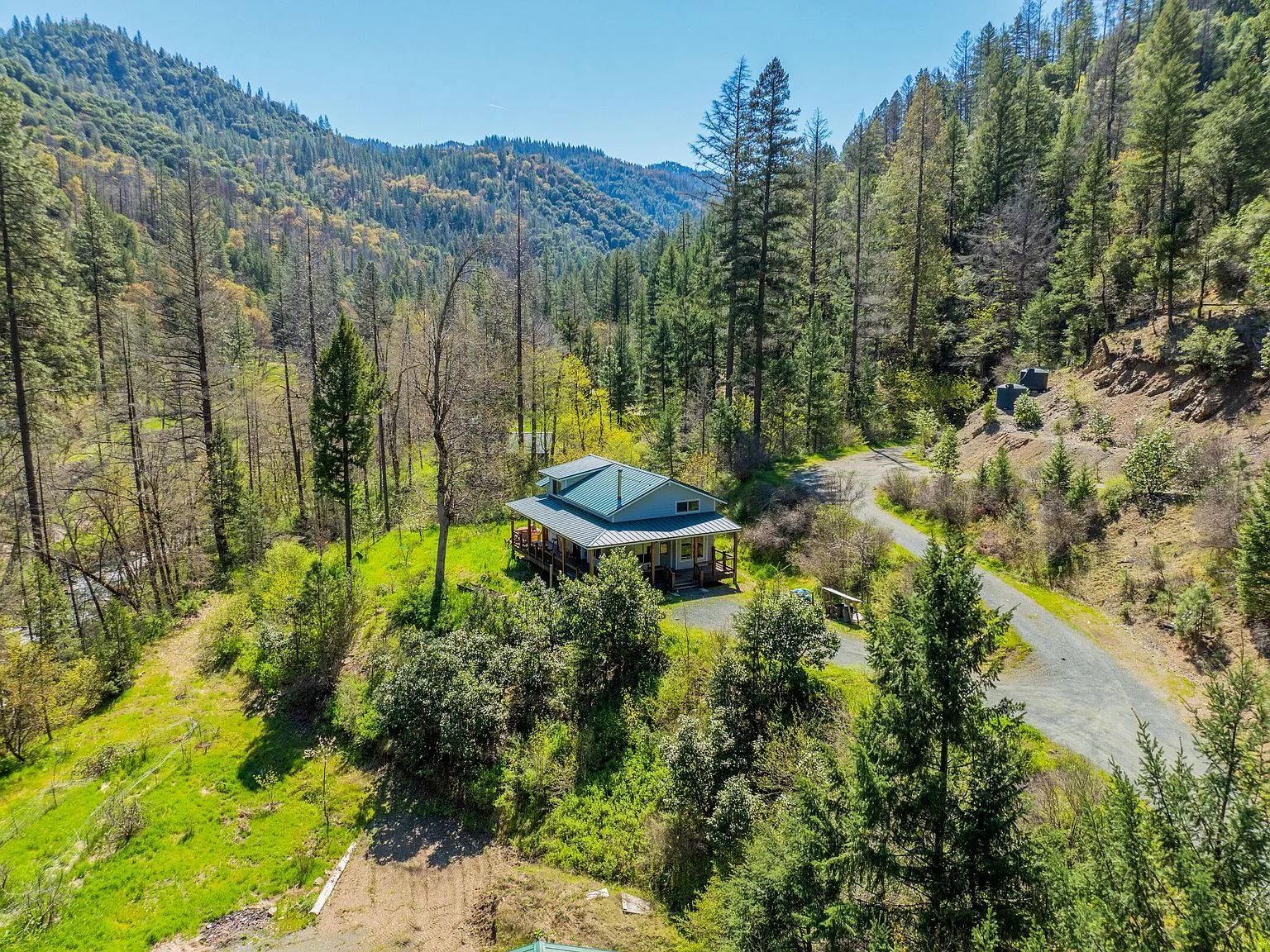 An aerial view of the house and shop nestled into the forested hillside