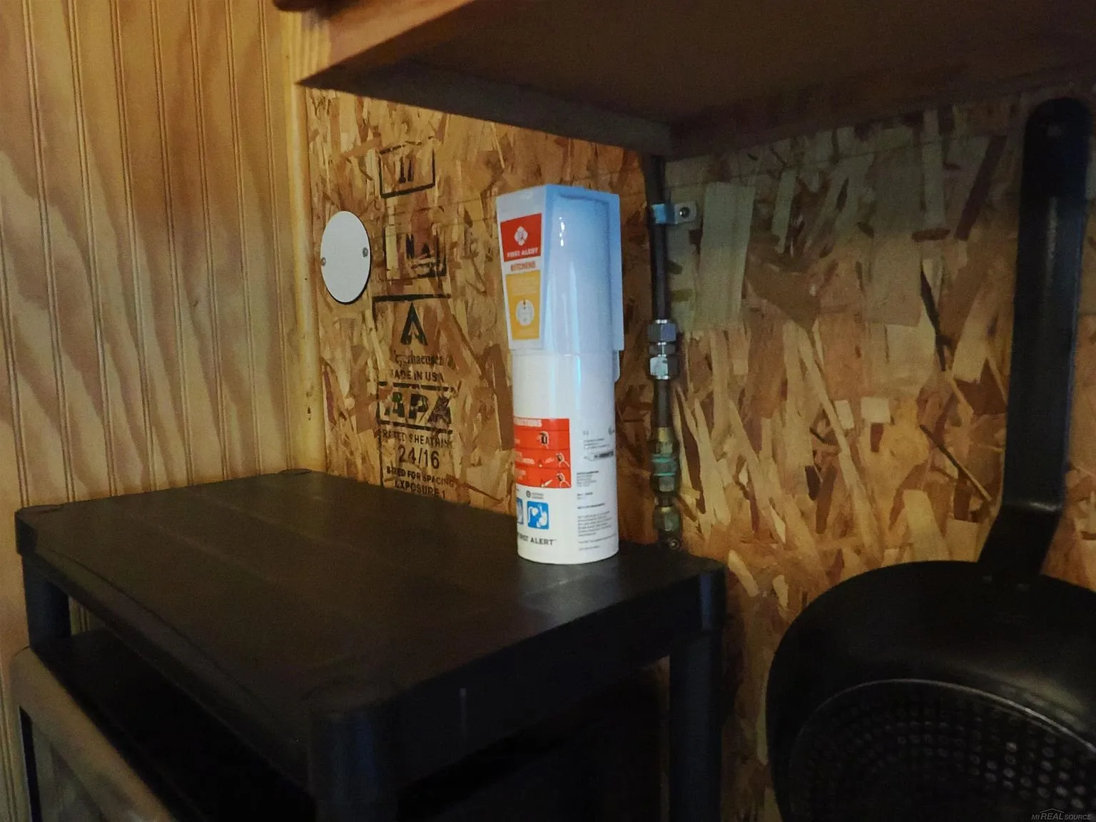 The propane line along the wall by the shelf and the cylinder