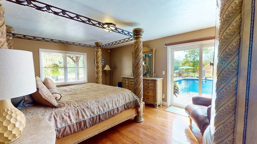 A bedroom with a bay window looking out toward the pool