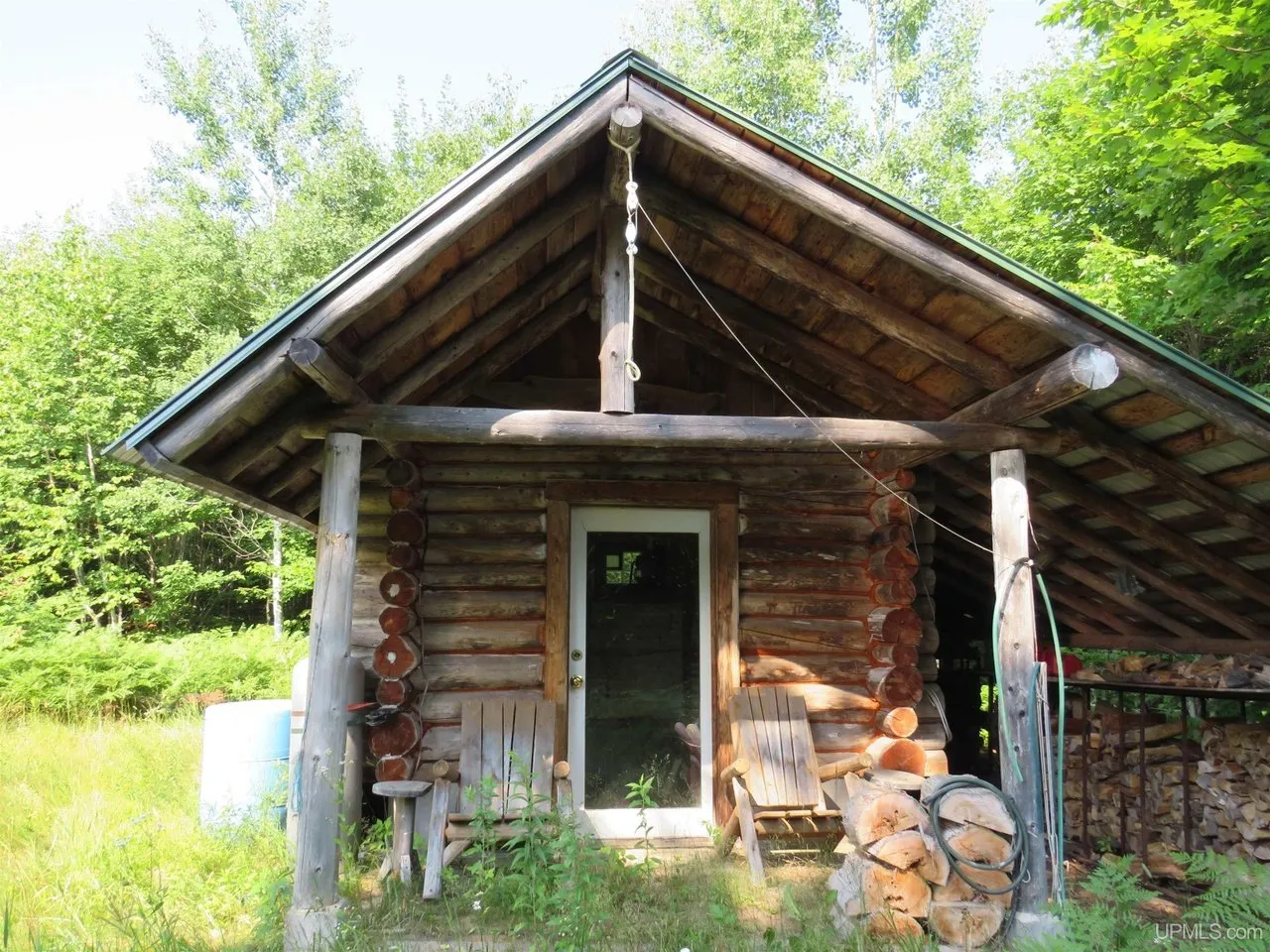 The log sauna building with a covered woodpile at one end