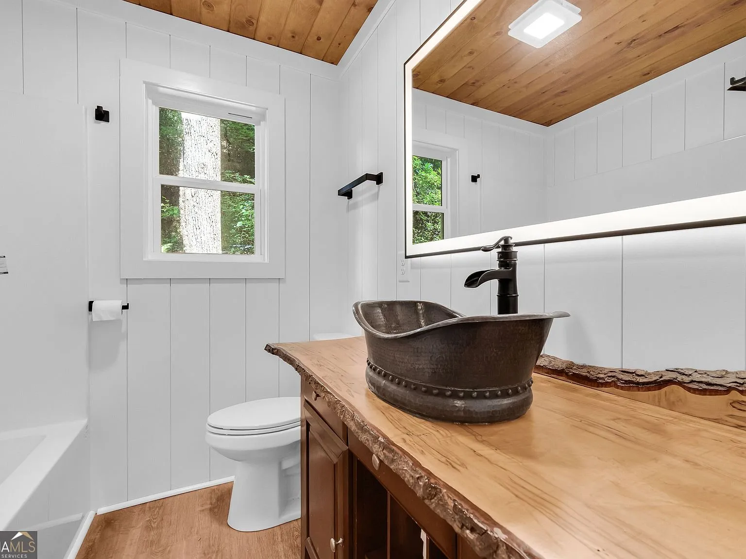 A bathroom with a glass-enclosed shower, granite-style vessel sink and wood vanity