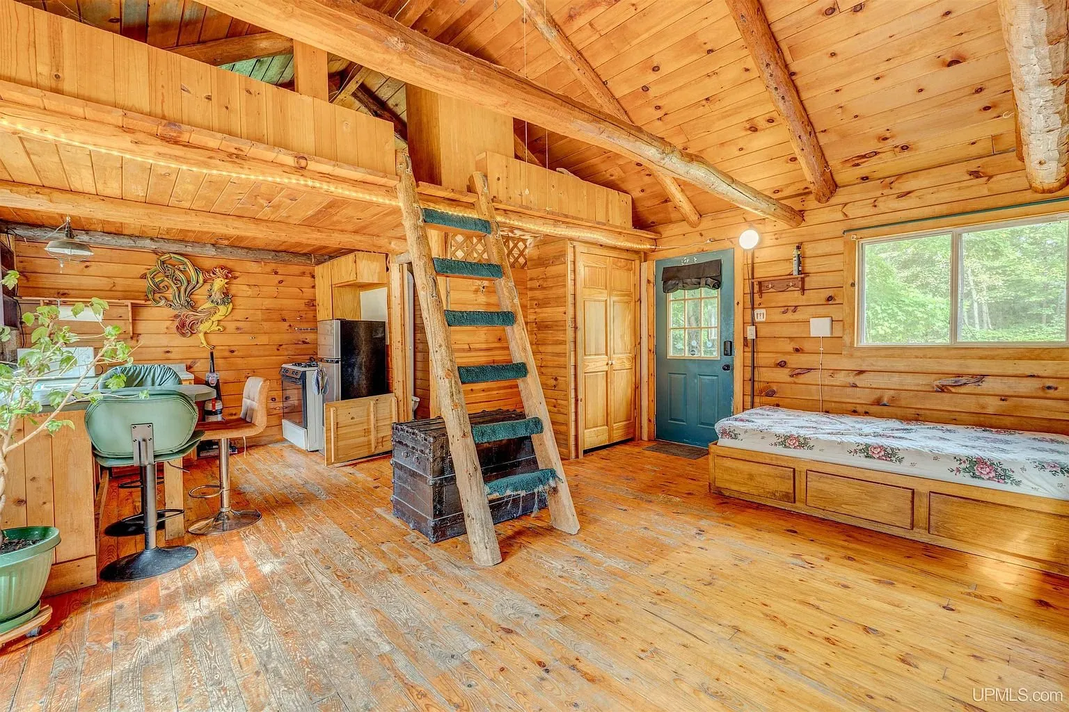 The main room with the ladder to the loft and a bed under the window