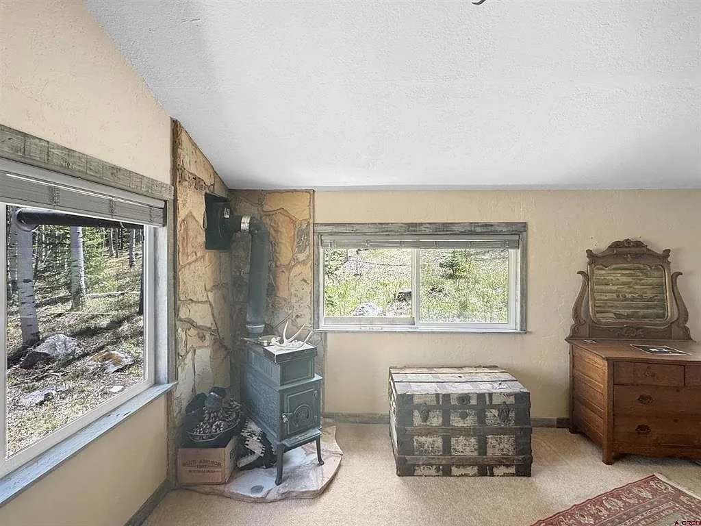 A bedroom with the wood stove, the window and the dresser
