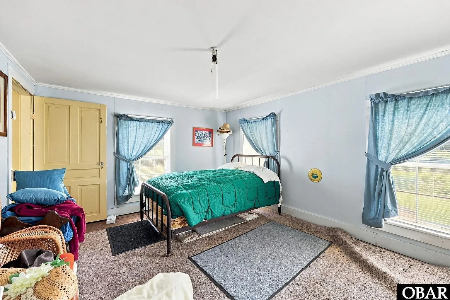A bedroom with a green bedspread and a carpeted floor
