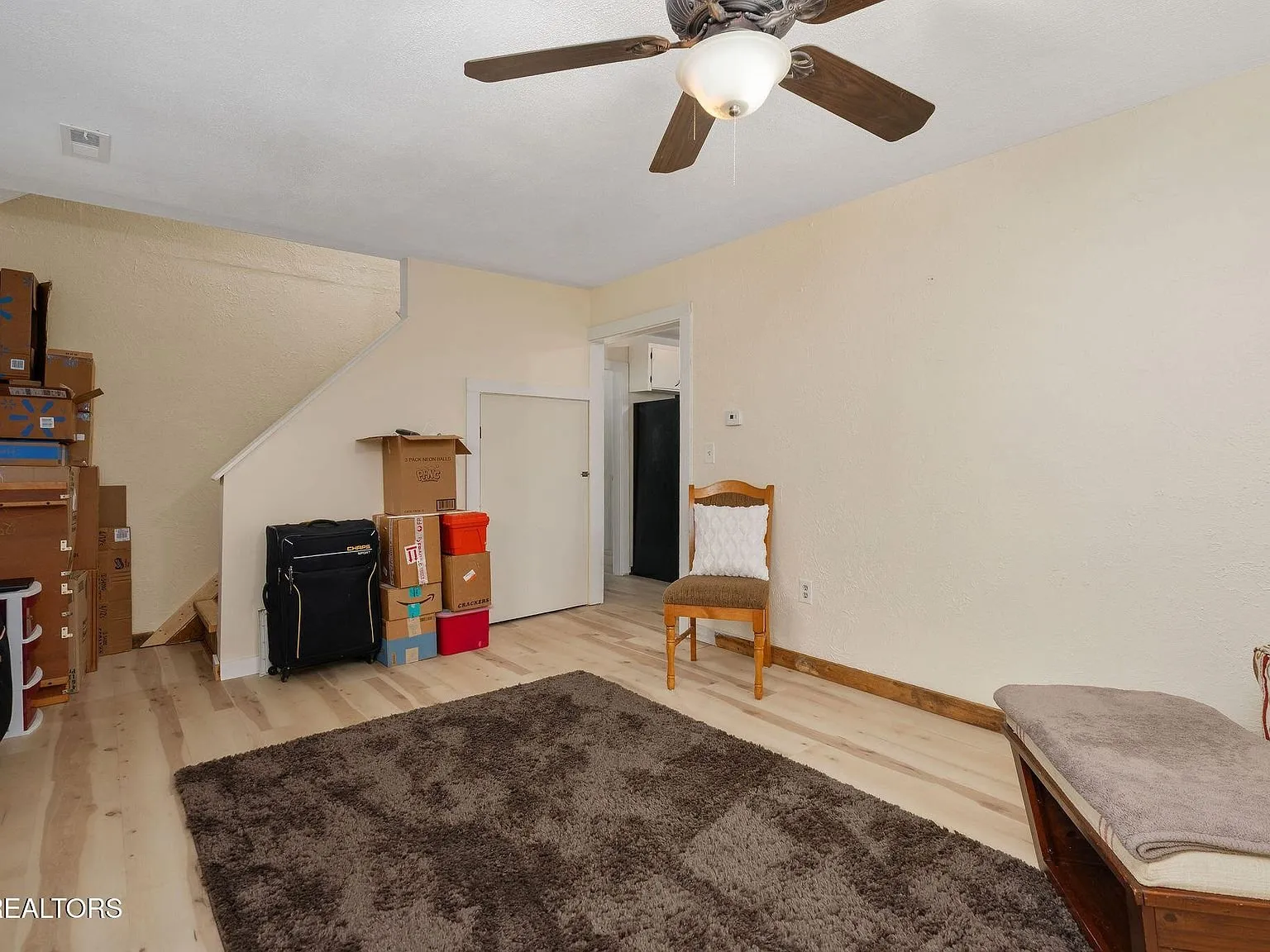 A bedroom with a made bed, curtains and wood-look flooring