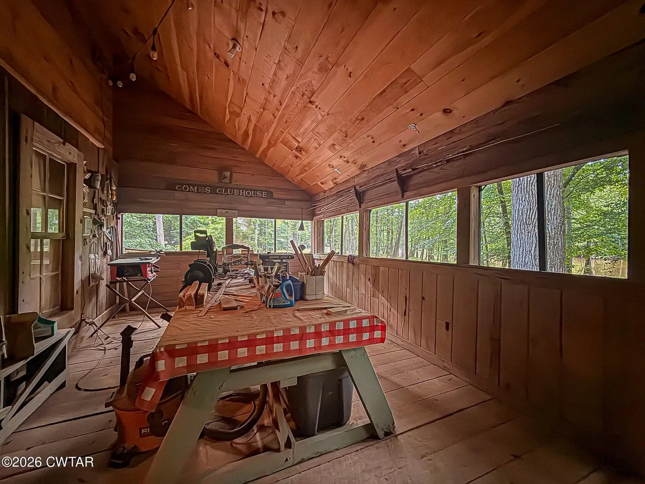 The screened porch with a picnic table under the wood ceiling