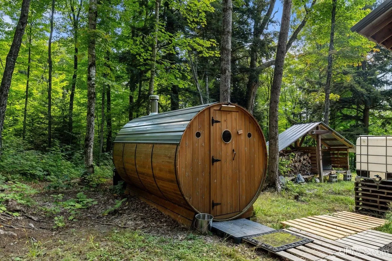 The barrel sauna sitting on its platform under the trees