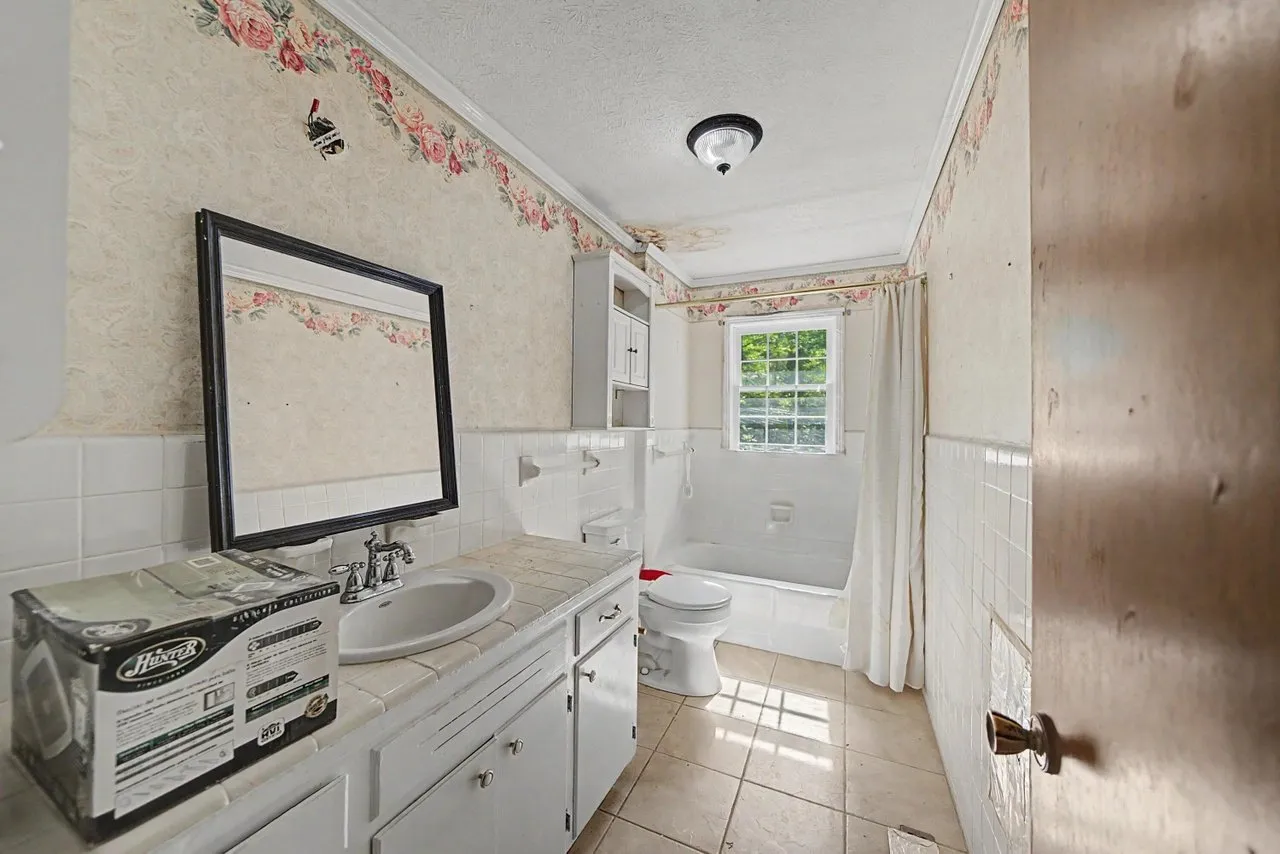 A bathroom with a vanity, mirror and tub