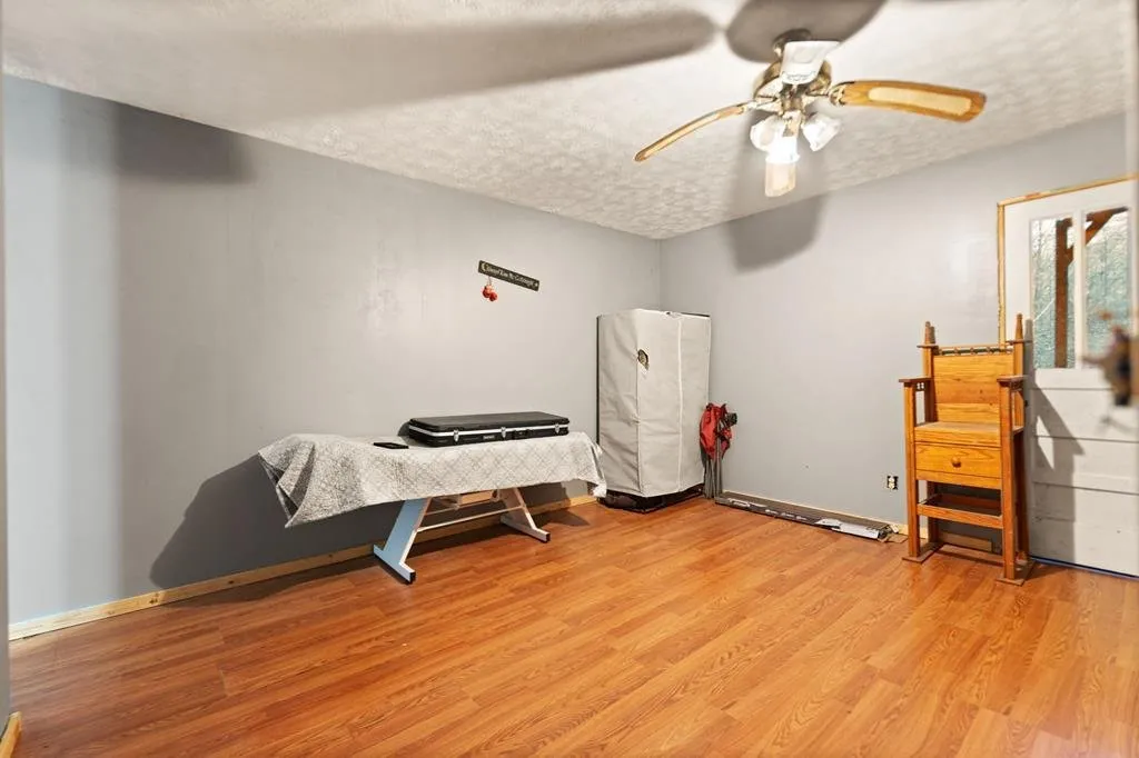 A second bedroom with grey walls, a mattress on the floor and a ceiling fan