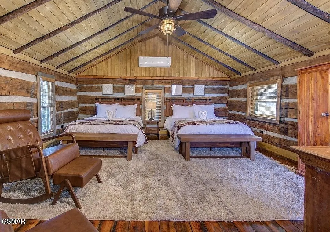 A room with two beds under an open beam cathedral ceiling