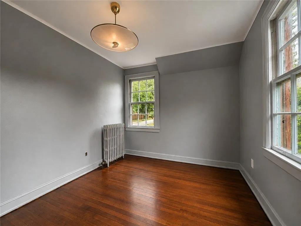 A gray bedroom with hardwood floors and a radiator