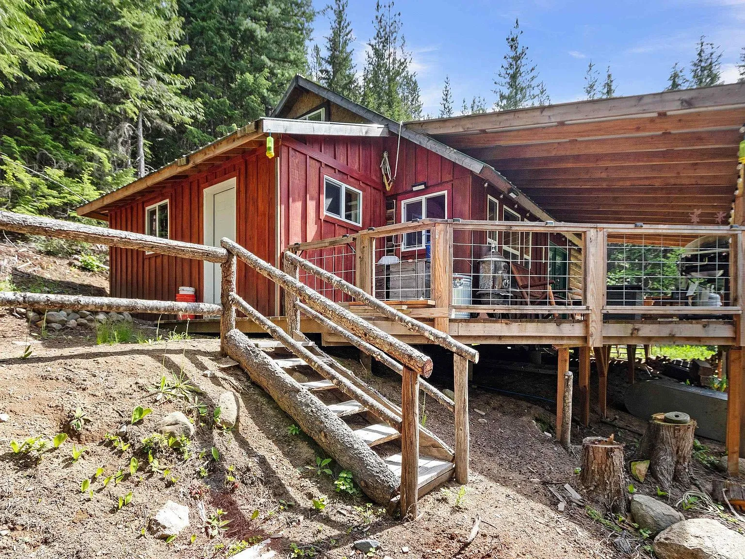 The cabin's red board-and-batten siding and covered deck, seen from the side yard