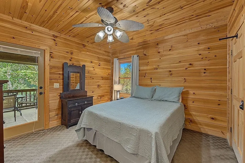 The main-level primary bedroom with a ceiling fan and deck access