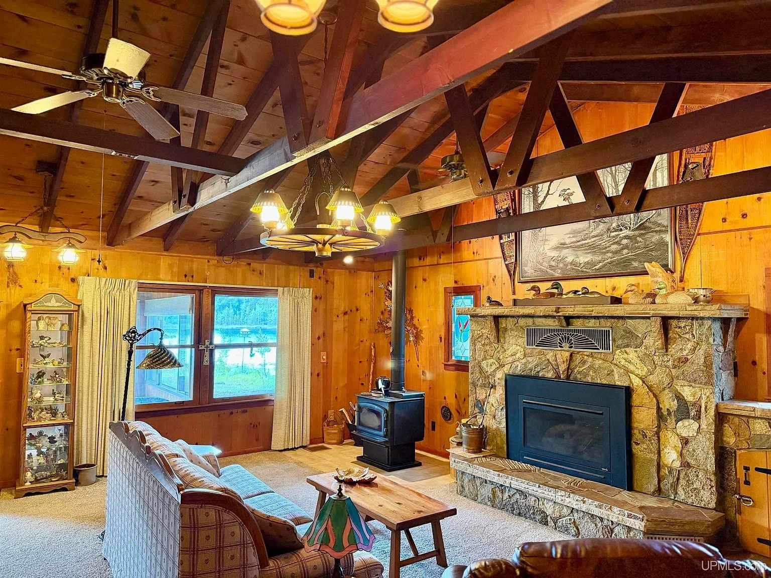 The living room with the stone fireplace, wood stove and exposed trusses