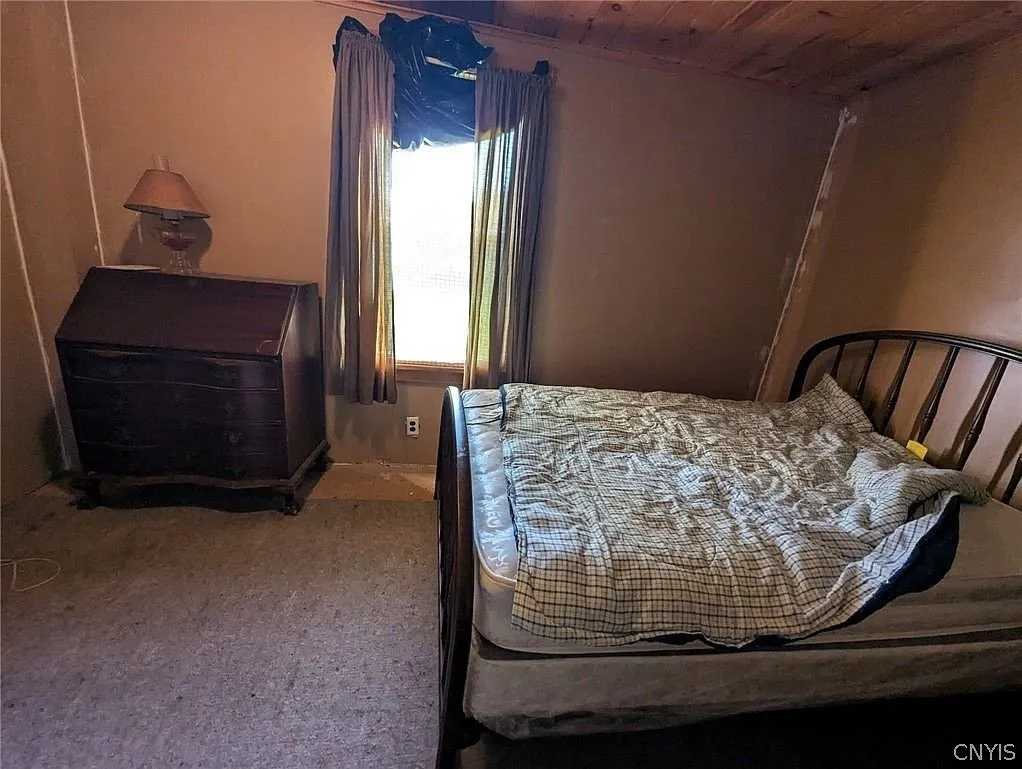 A bedroom with a dresser and a bed by the window