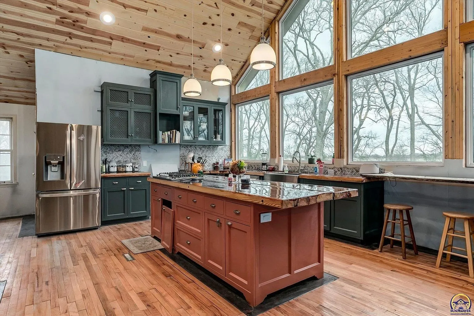 The kitchen with the island, the stainless refrigerator and the pine ceiling