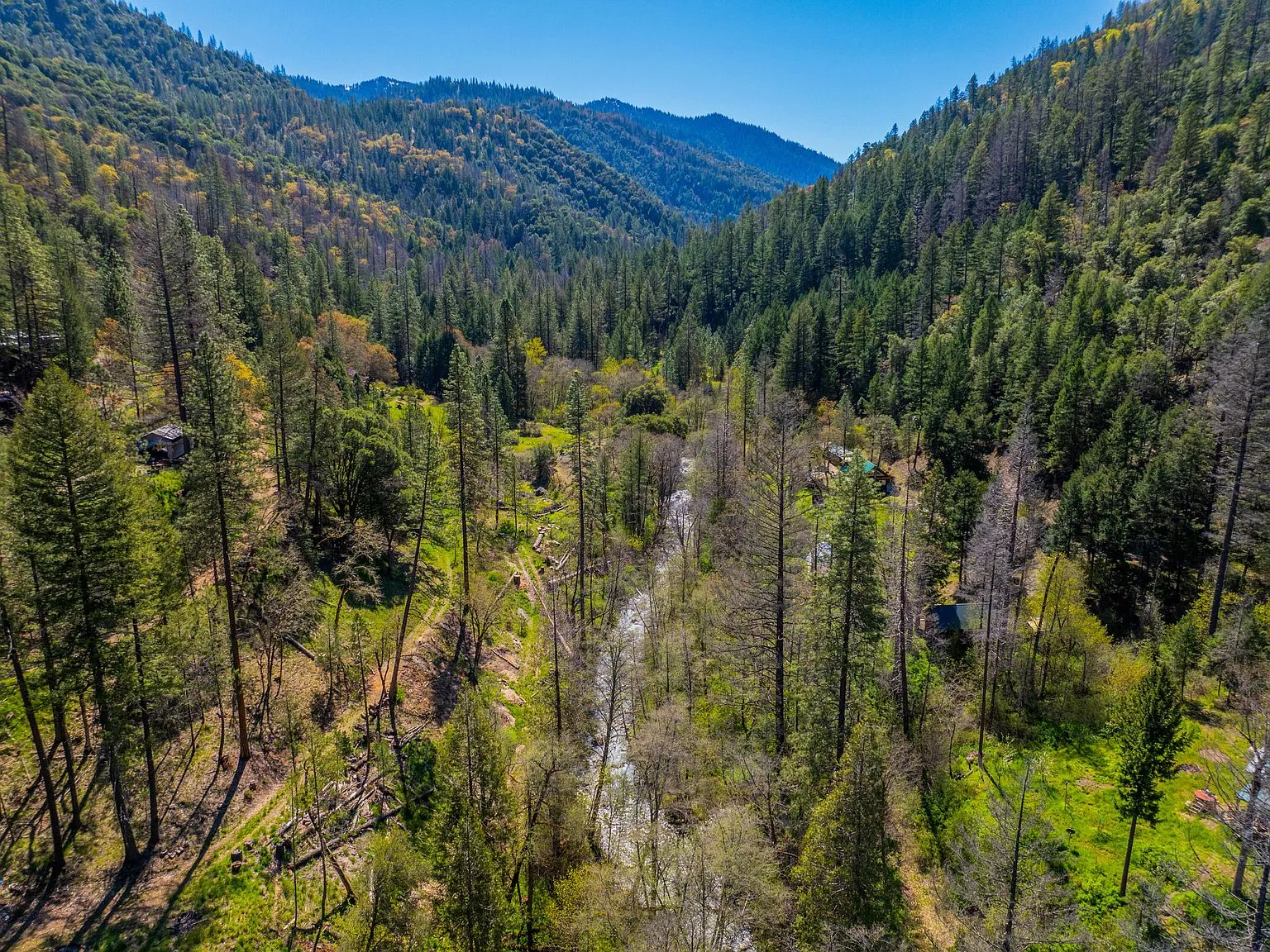 A wide aerial view of the timbered ridgelines surrounding the property