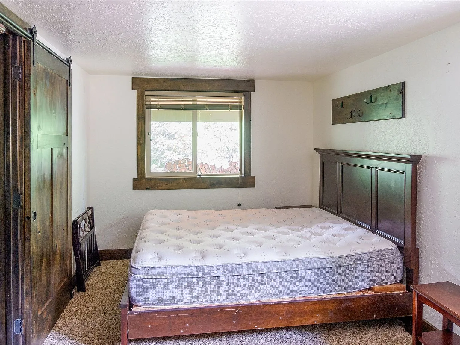 A bedroom with a dark wood bed frame and a barn-style closet door