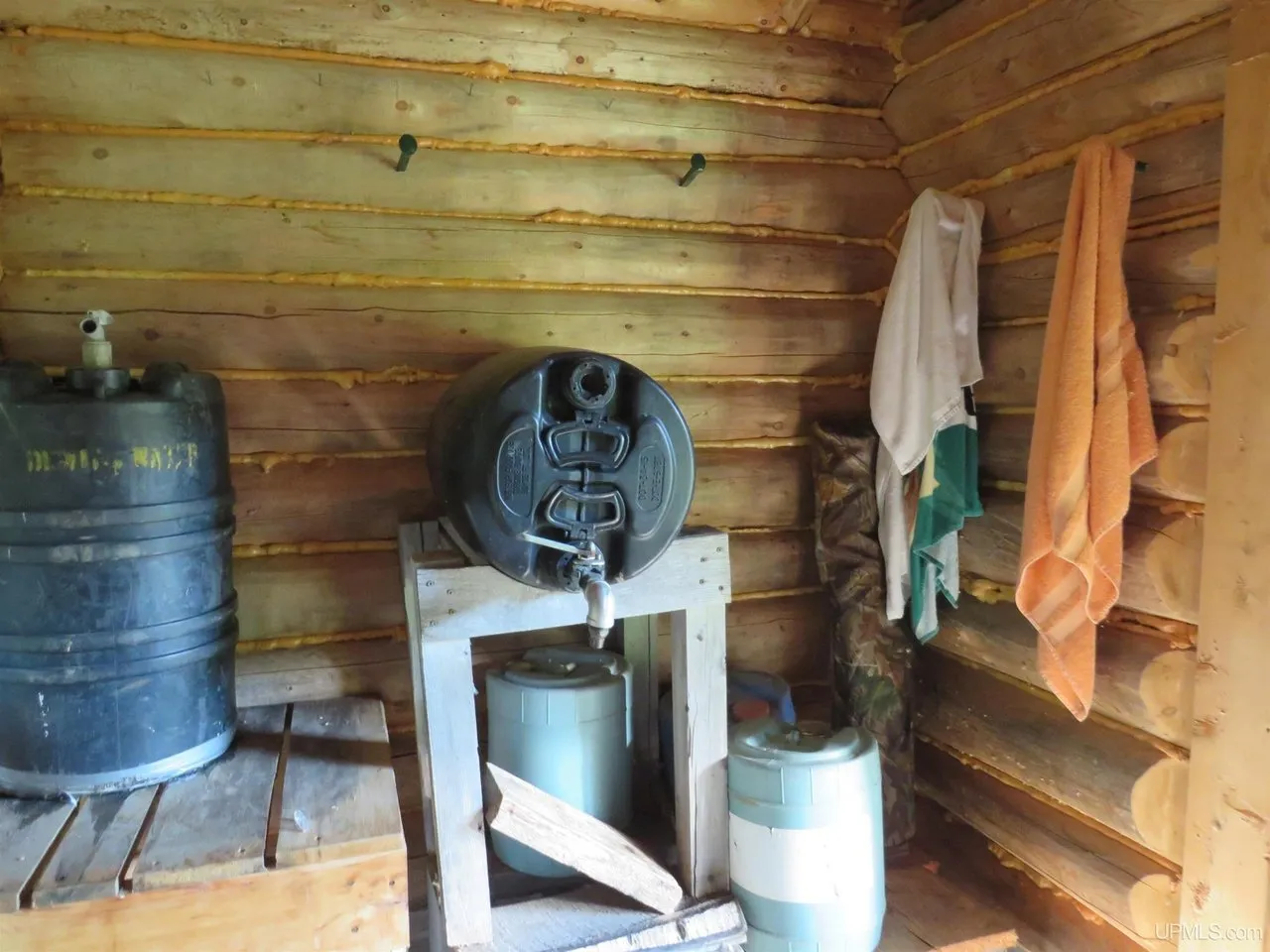 The sauna's changing room with water tanks and a hand pump