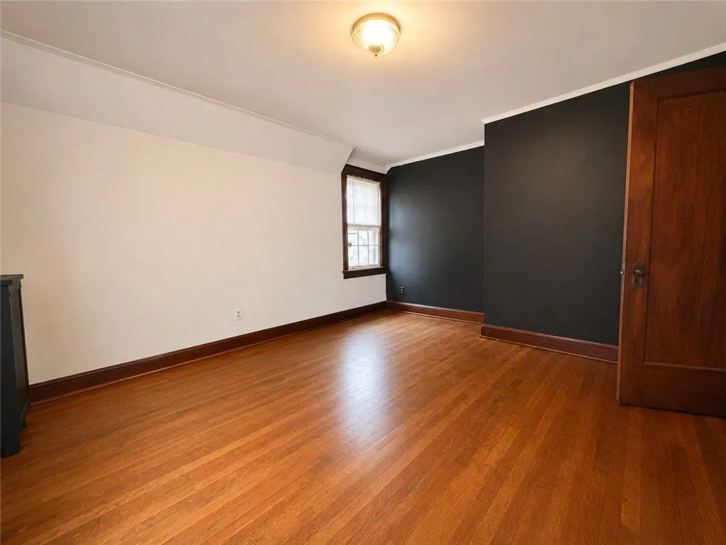 A bedroom with a navy wall and hardwood floors