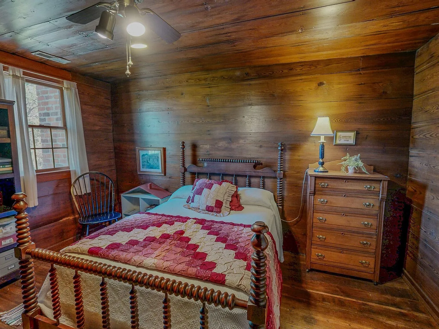 A wood-paneled bedroom with a spindle bed and a quilt