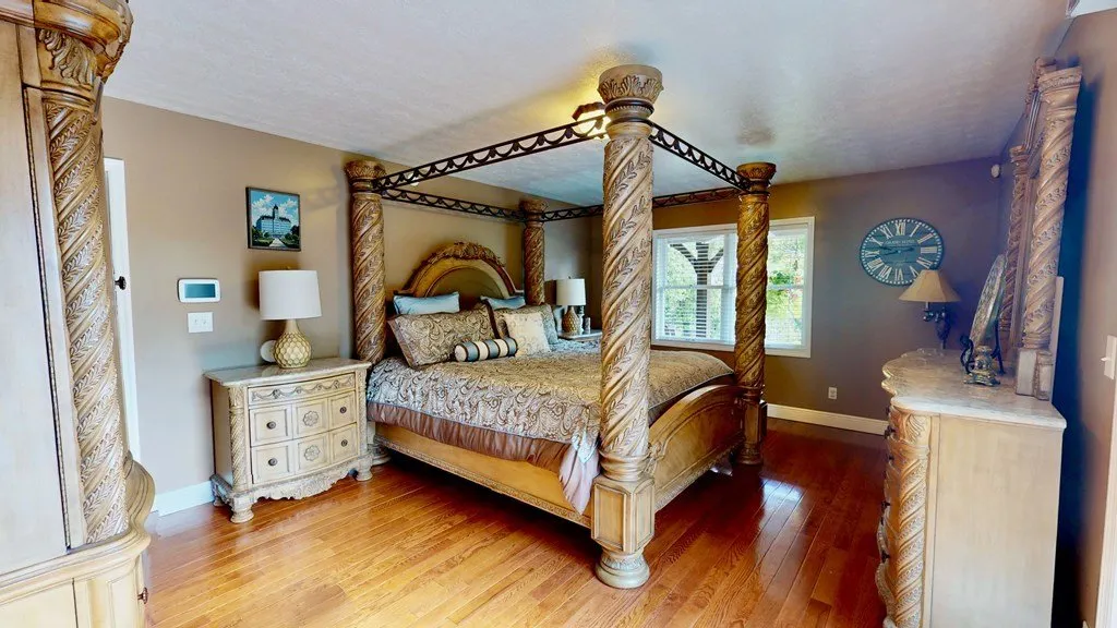 The main bedroom with a four-poster bed and hardwood floors