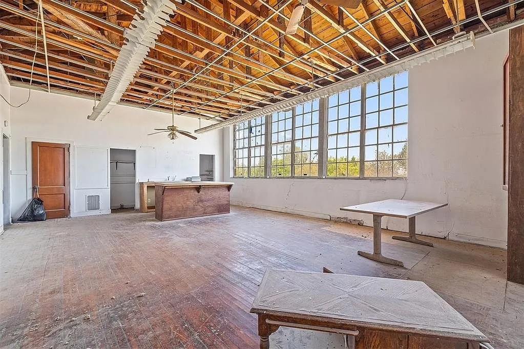 A classroom with the tables, the open ceiling and the windows