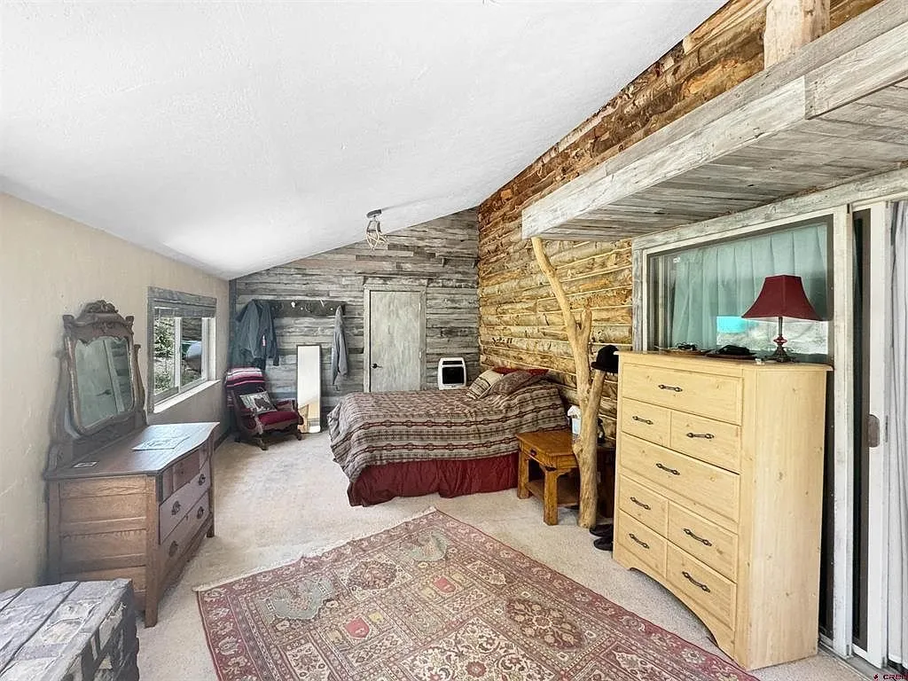 A bedroom with the bed, the dresser and the glass door to the deck
