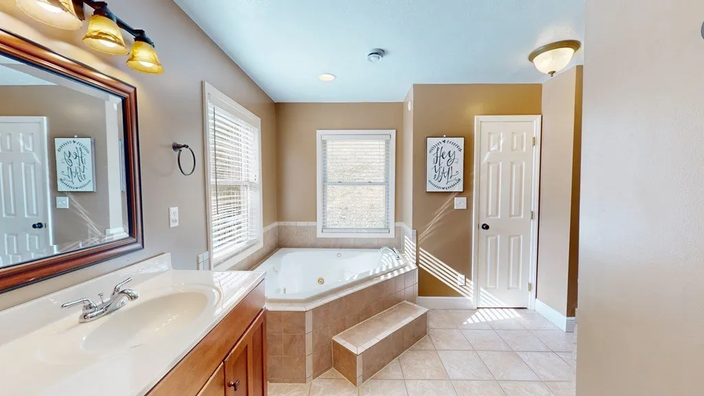 The ensuite bath with a corner soaking tub and tile surround