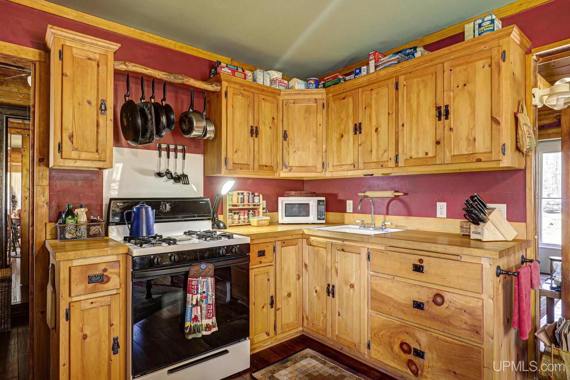 The kitchen with pine cabinets, a range and a microwave