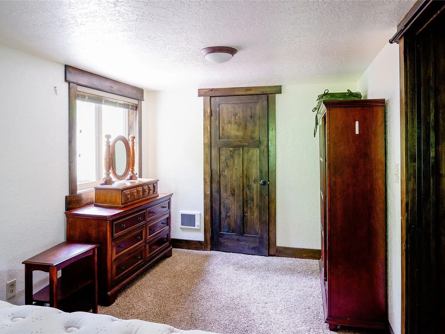 The bedroom's dresser, mirror and armoire along the wall